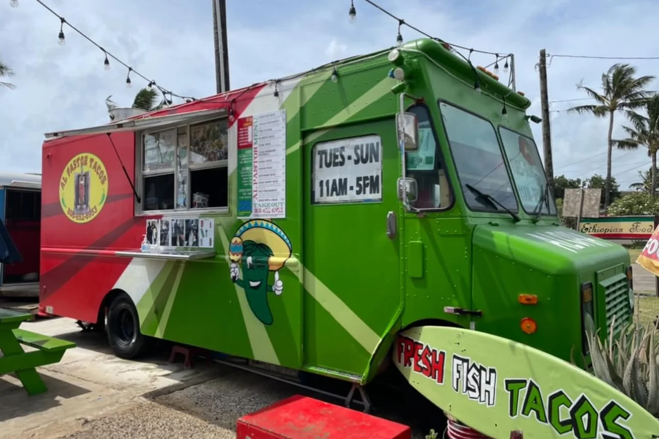 The green and red Al Pastor Tacos food truck on Kuhio Highway with its Fresh Fish Tacos sign